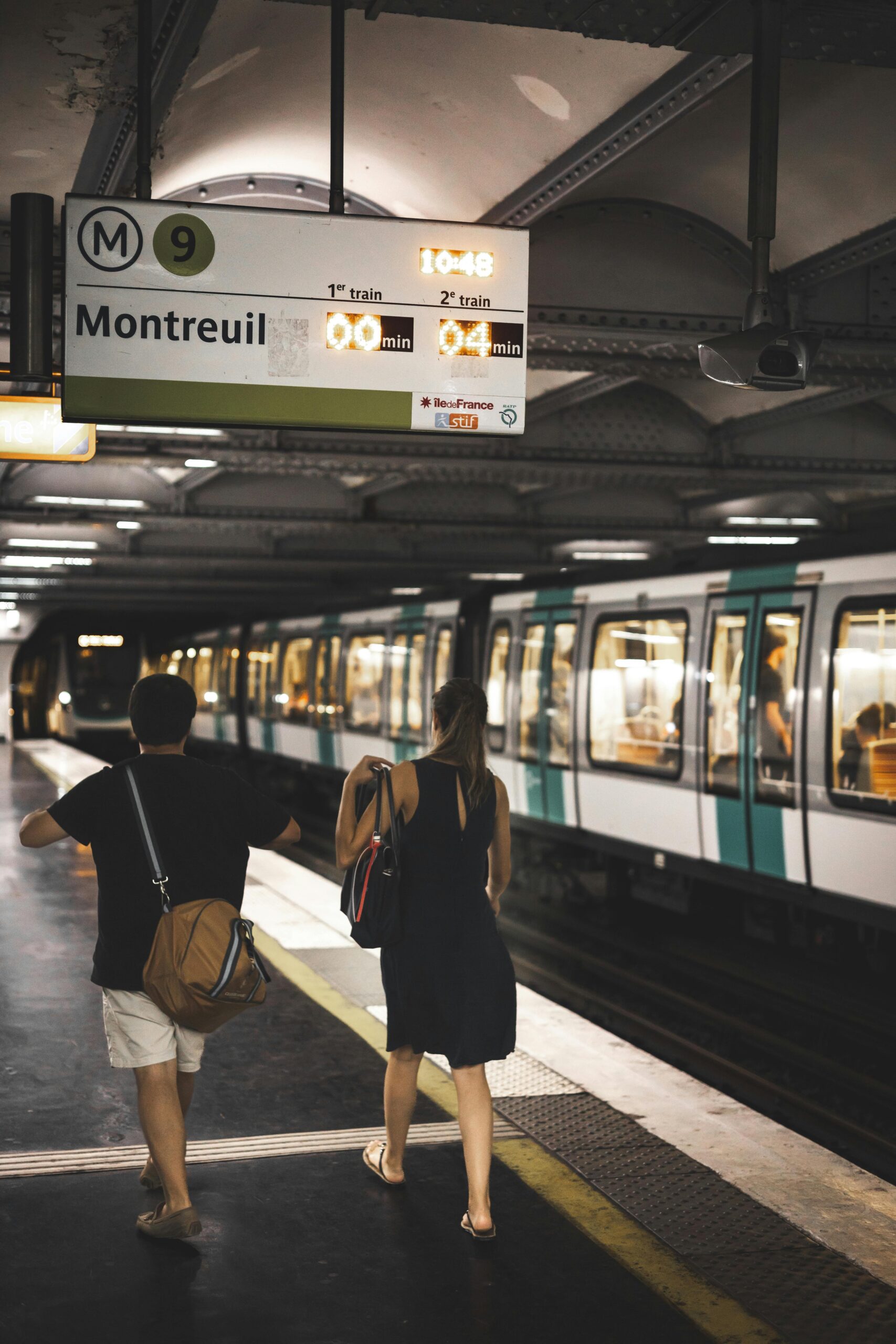 A couple walks through a Paris subway station at night, captured in a candid moment.