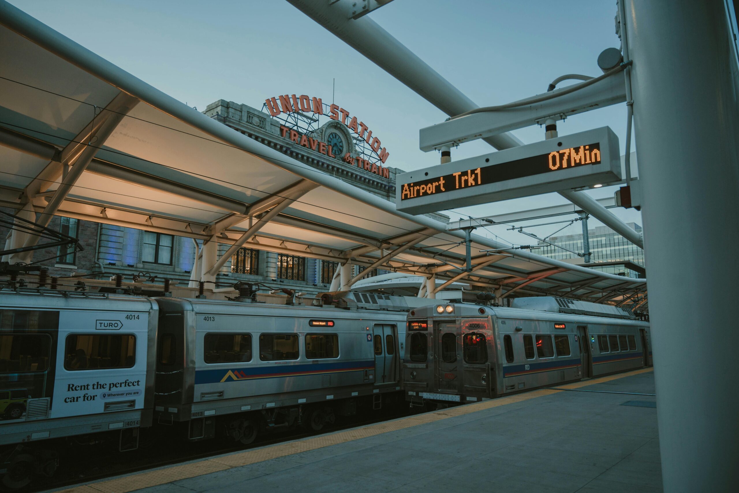 Evening train at Denver Union Station with iconic sign and transit information display.